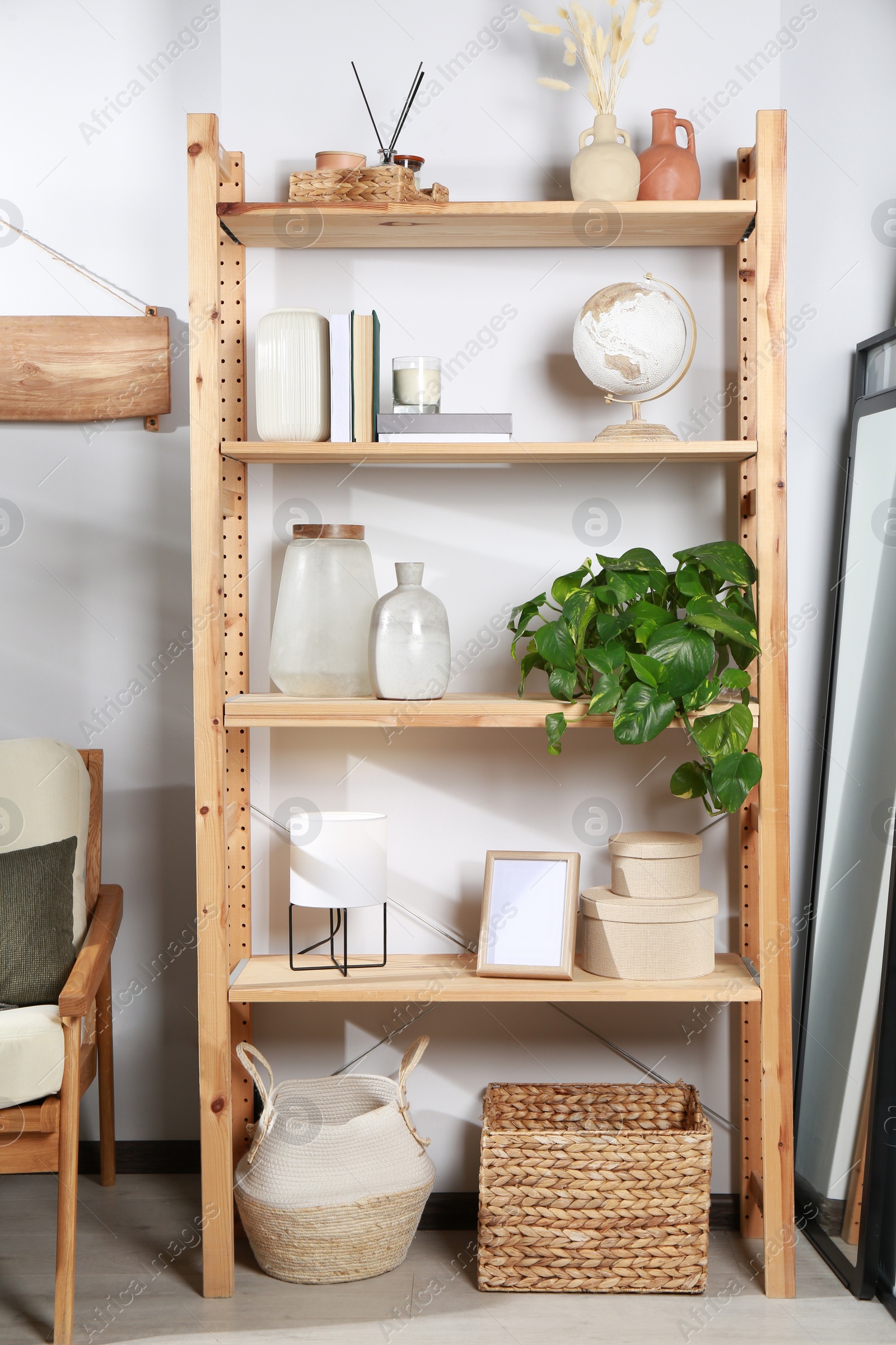 Photo of Wooden shelving unit with home decor near light wall in room