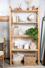 Photo of Wooden shelving unit with home decor near light wall in room