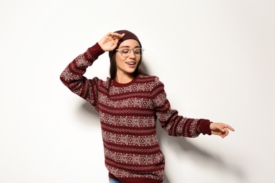 Photo of Young woman in warm sweater and hat on white background. Celebrating Christmas