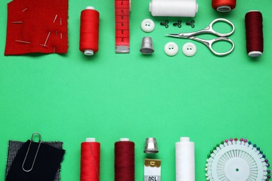 Photo of Flat lay composition with thimbles and different sewing tools on green background. Space for text