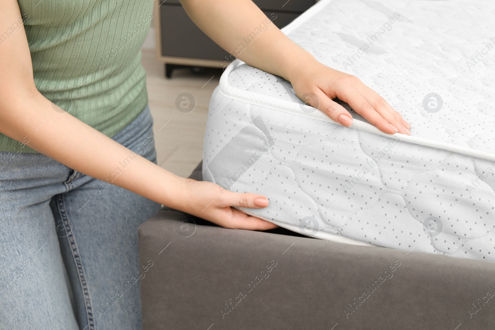 Photo of Woman putting new soft mattress on bed indoors, closeup