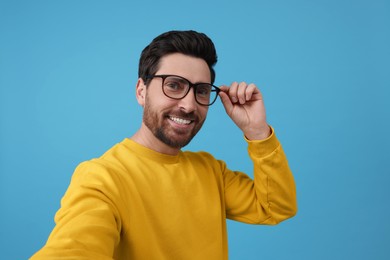 Smiling man taking selfie on light blue background