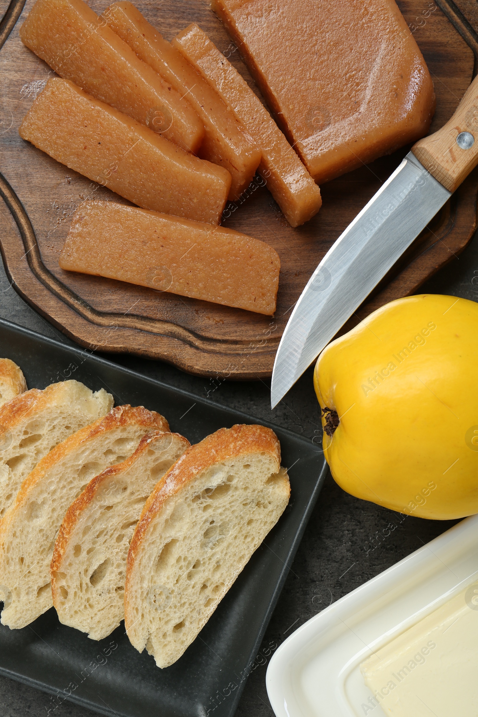 Photo of Delicious quince paste, bread, butter and fresh fruit on grey table, flat lay