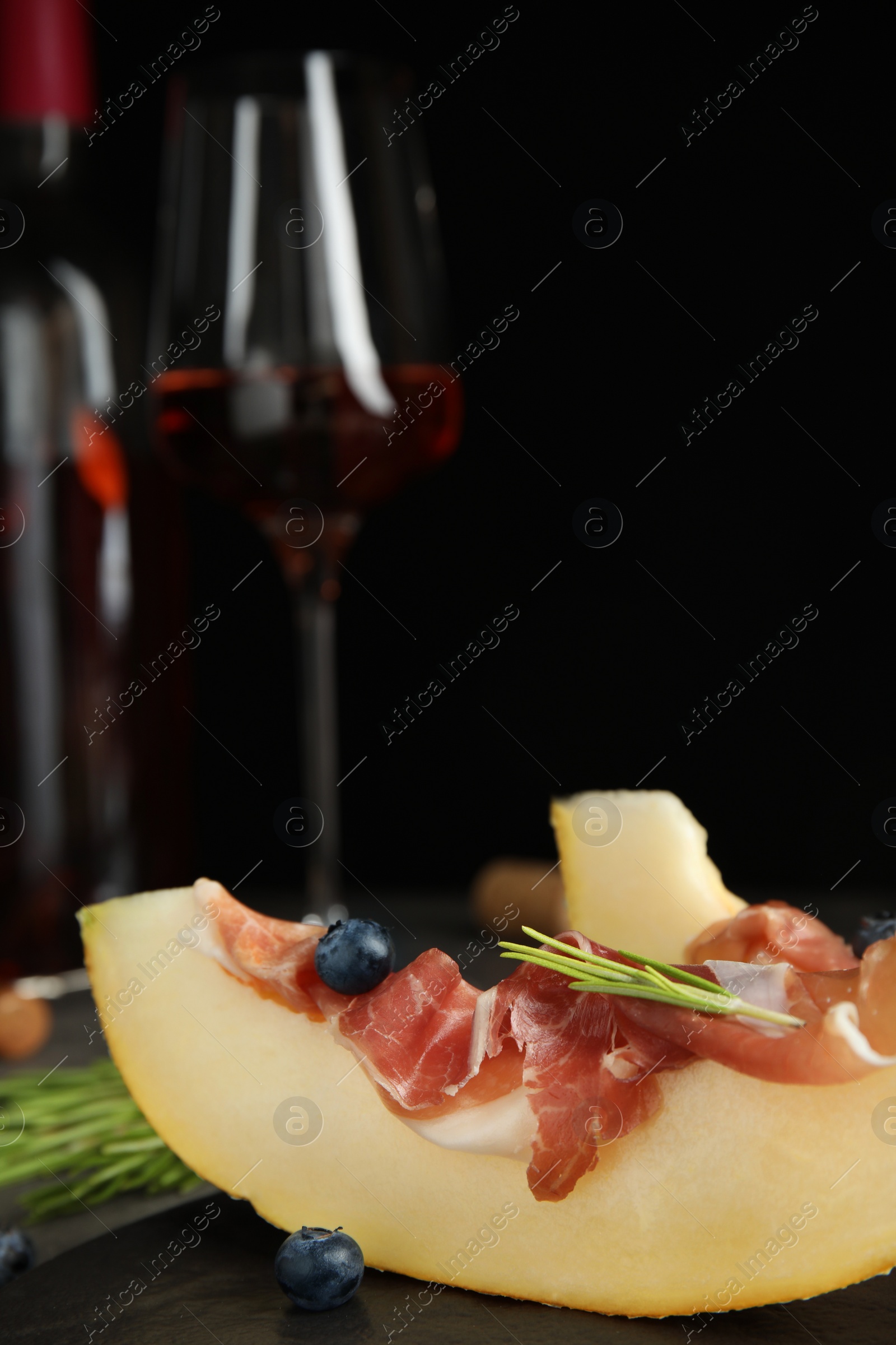 Photo of Melon with prosciutto, blueberries and rosemary on table