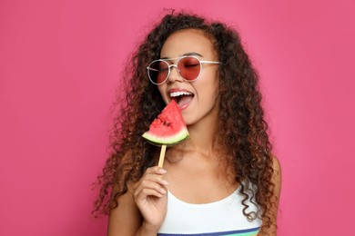 Photo of Beautiful young African American woman eating watermelon on crimson background