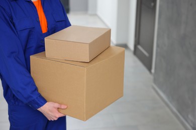 Courier with cardboard boxes in hallway, closeup