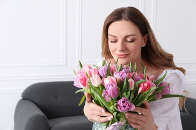 Photo of Young woman with bouquet of beautiful tulips indoors