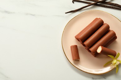 Photo of Glazed curd cheese bars, vanilla pods and flower on white marble table, top view. Space for text