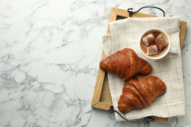 Photo of Tasty croissants served with cup of hot drink on white marble table, top view. Space for text