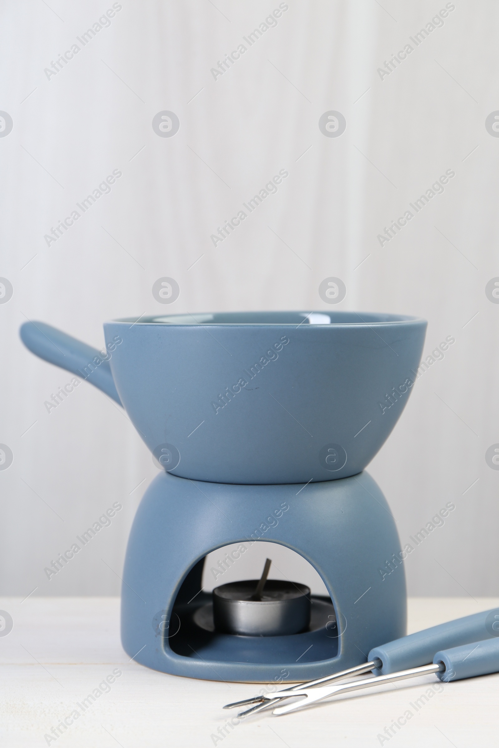 Photo of Fondue set on white wooden table, space for text