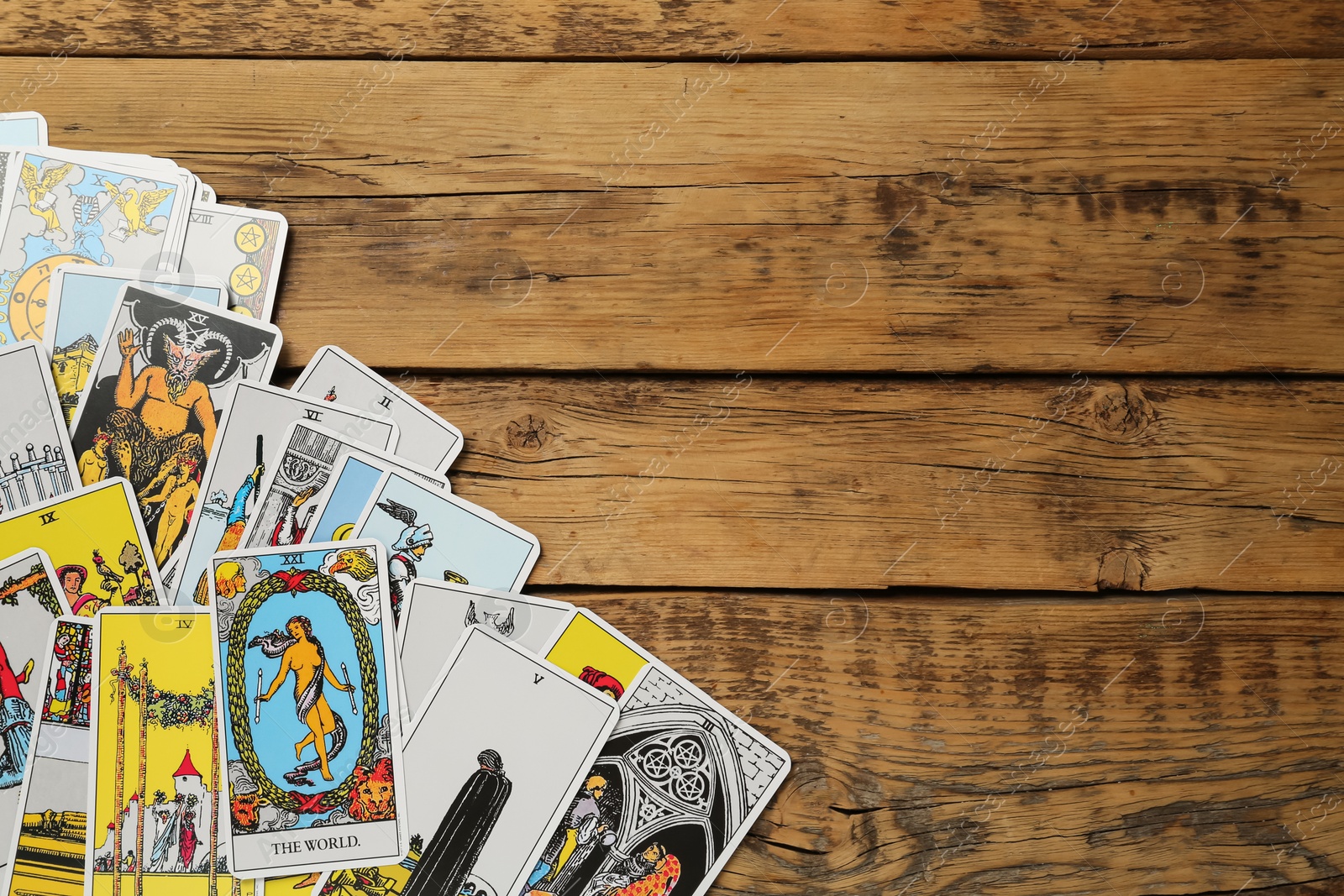 Photo of Tarot cards on wooden table, top view. Space for text