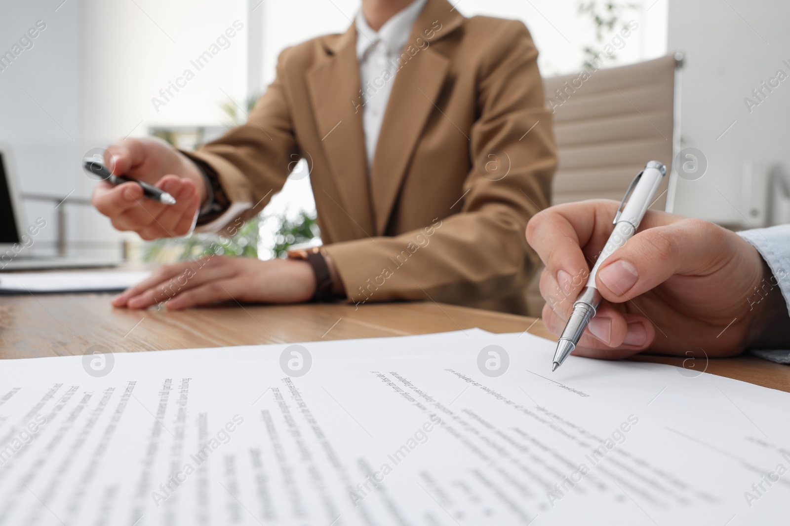 Photo of Businesspeople signing contract at table in office, closeup