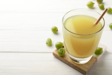 Tasty gooseberry juice on white wooden table. Space for text