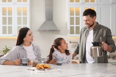 Photo of Happy family having breakfast at table in kitchen. Adoption concept