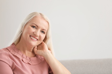 Portrait of beautiful older woman against light background with space for text