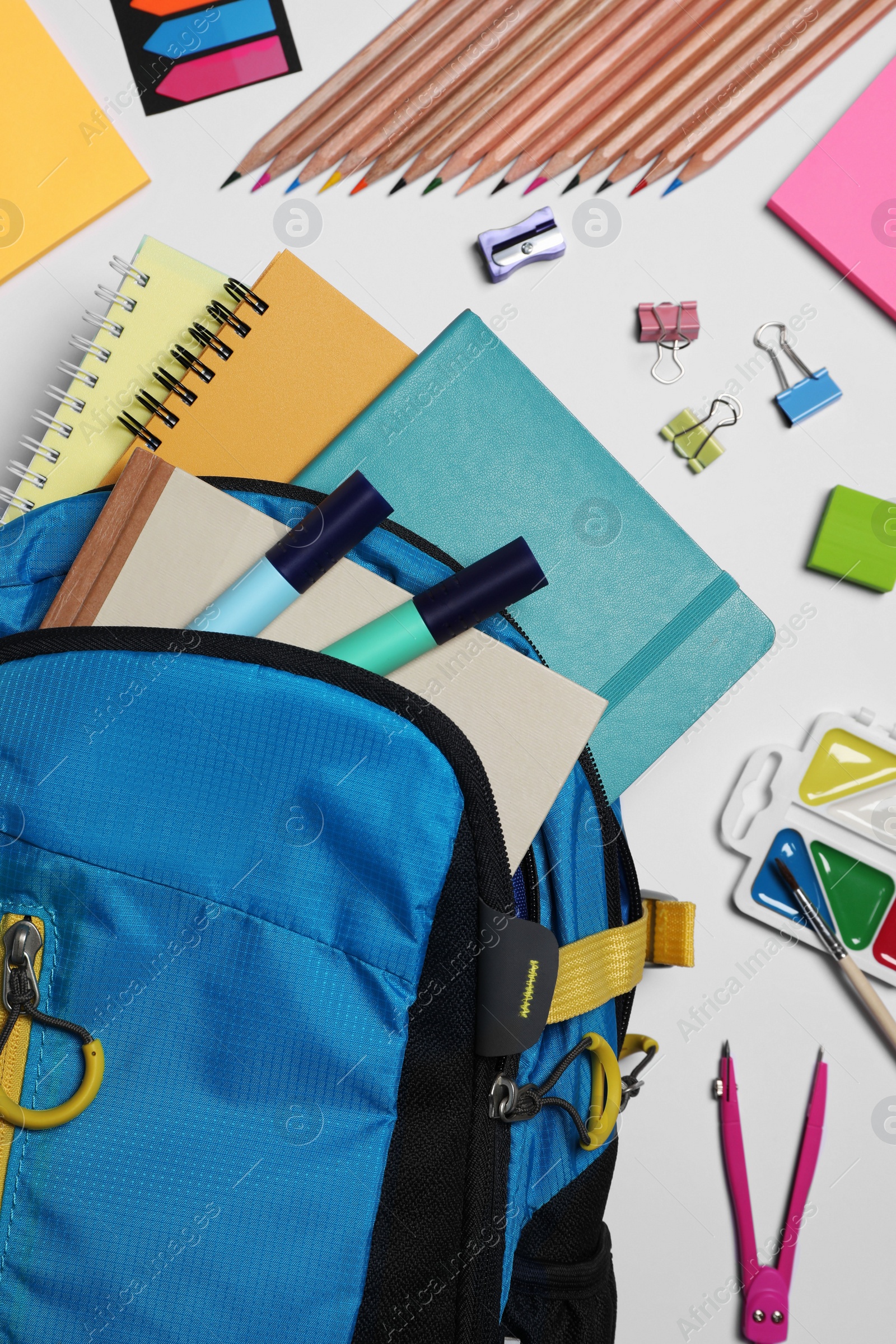 Photo of Backpack with different school stationery on white background, flat lay