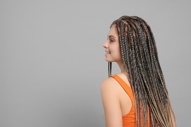 Beautiful woman with long african braids on grey background, space for text