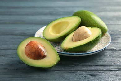 Photo of Plate with ripe avocados on wooden background