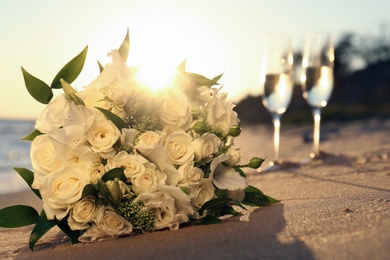 Photo of Beautiful wedding bouquet on sandy beach at sunset