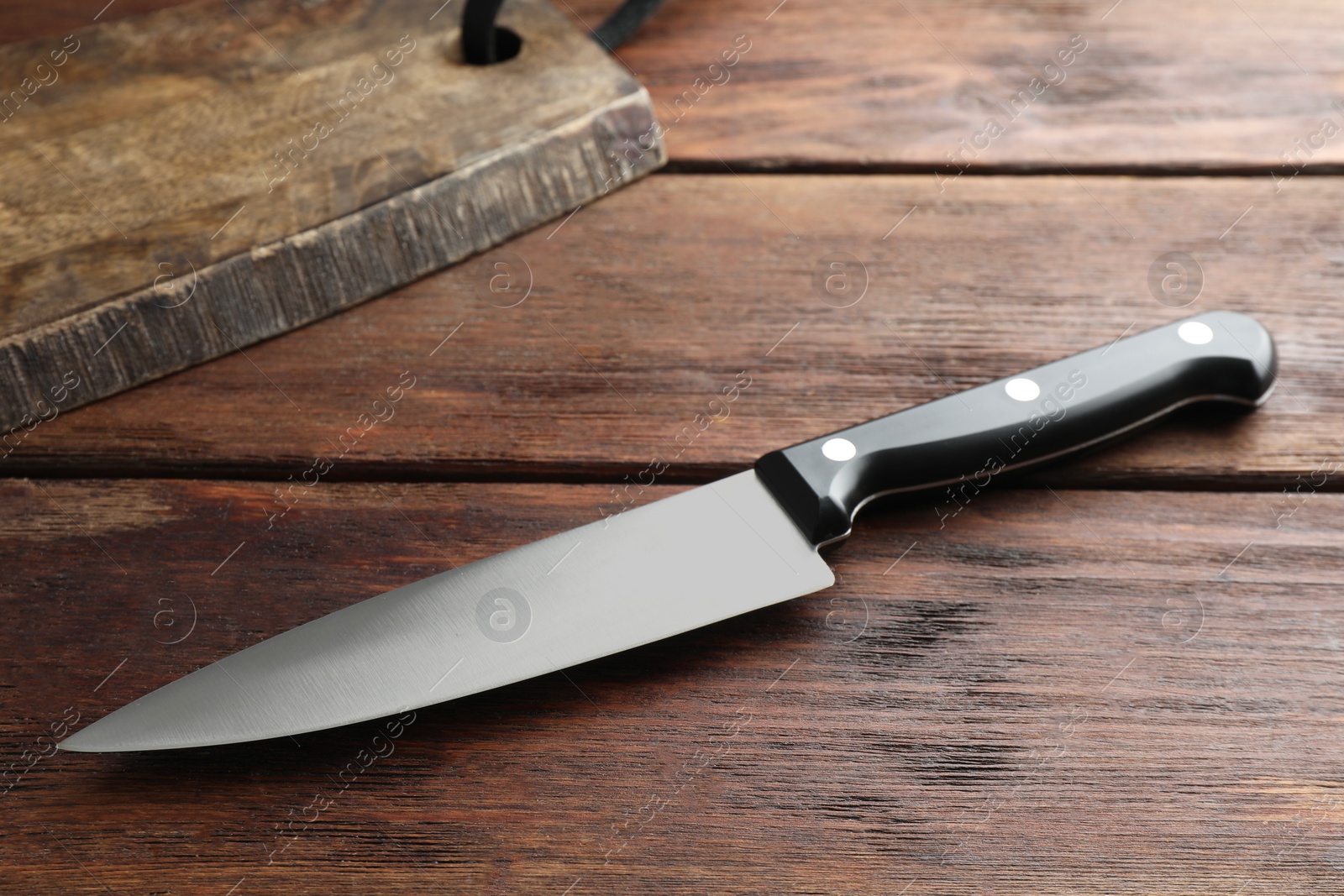 Photo of One sharp knife on wooden table, closeup