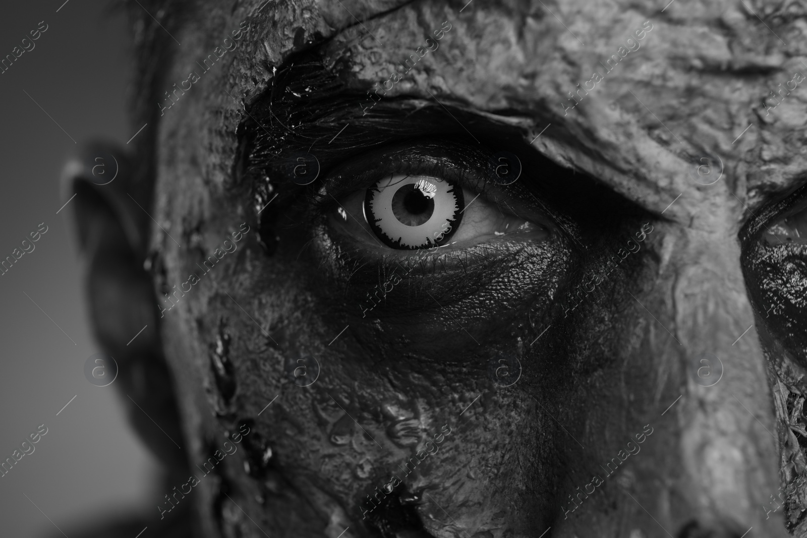 Photo of Closeup view of scary zombie on dark background, black and white effect. Halloween monster