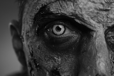 Photo of Closeup view of scary zombie on dark background, black and white effect. Halloween monster