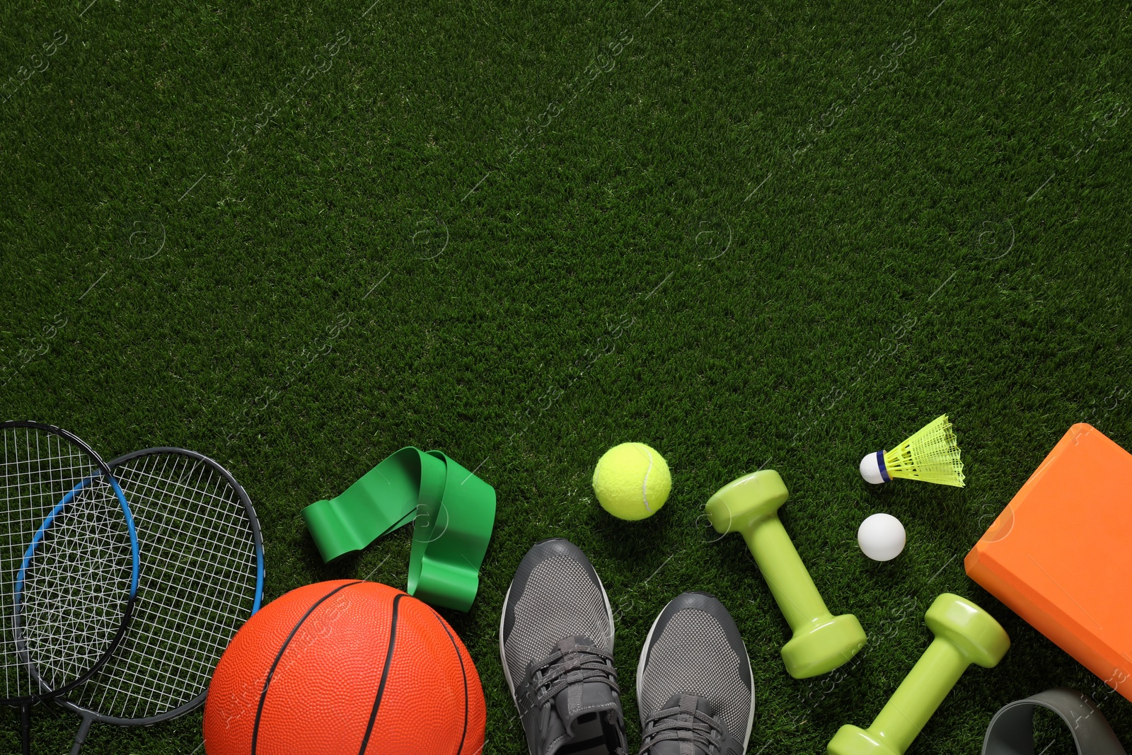 Photo of Different sport tools on green grass, flat lay. Space for text