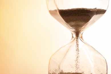 Photo of Hourglass with flowing sand on light background, closeup. Time management