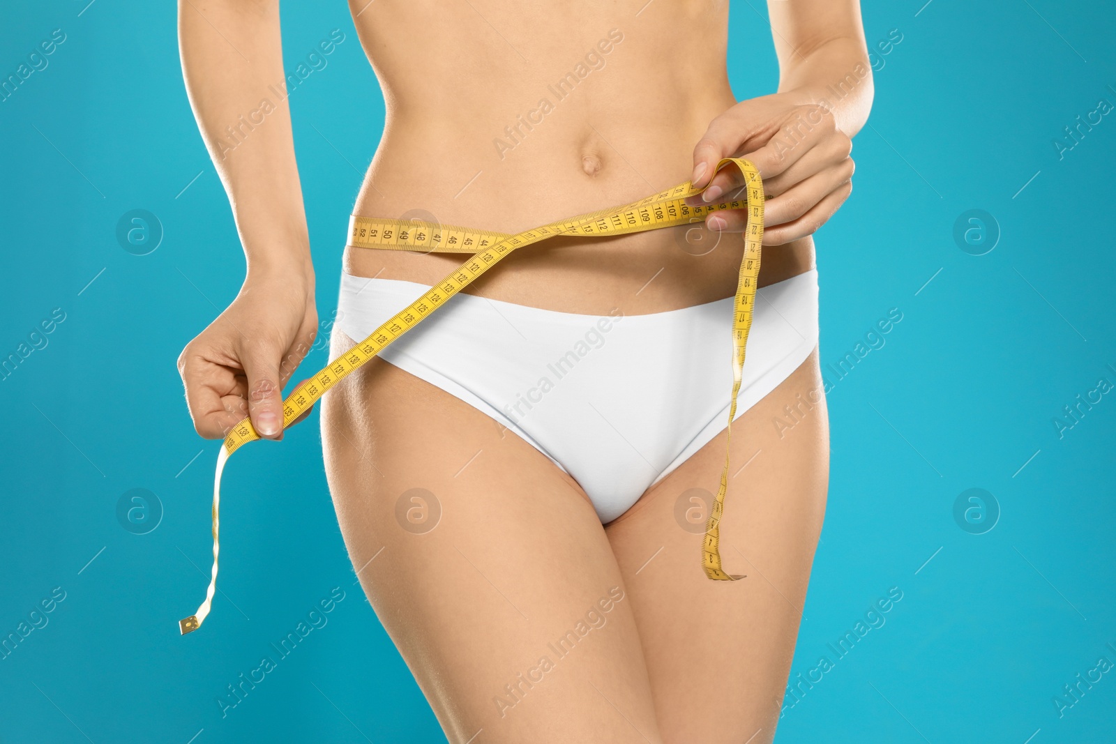 Photo of Slim young woman with smooth gentle skin in underwear measuring body on color background, closeup