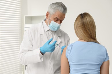 Doctor giving hepatitis vaccine to patient in clinic