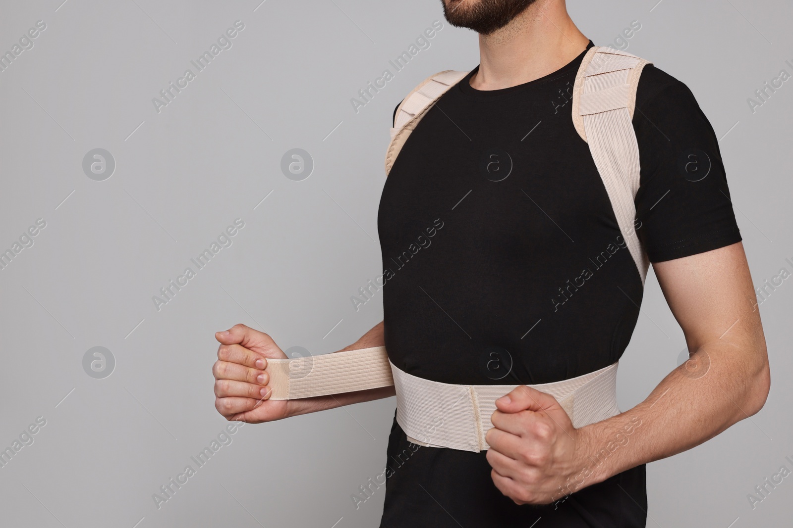 Photo of Closeup view of man with orthopedic corset on grey background. Space for text