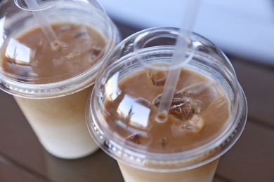 Plastic takeaway cups of delicious iced coffee on table, closeup