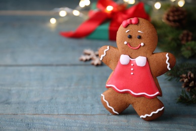 Gingerbread girl on blue wooden table, closeup. Space for text