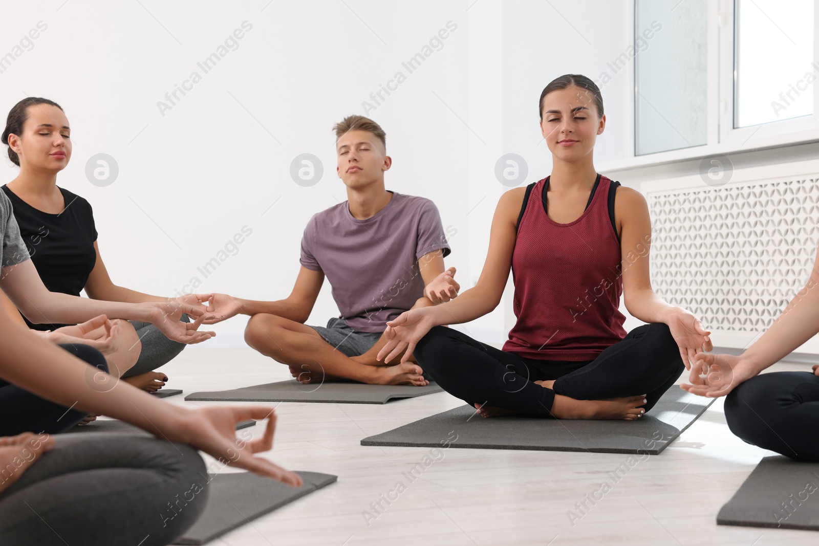 Photo of Group of people practicing yoga on mats indoors