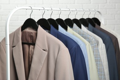 Dry-cleaning service. Many different clothes hanging on rack against white background, closeup