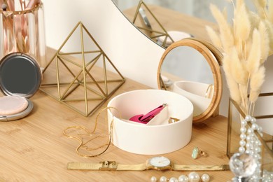 Photo of Jewelry box with many different accessories, wristwatch and decor on wooden table