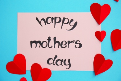 Photo of Greeting card with phrase "HAPPY MOTHER'S DAY" and paper hearts on color background