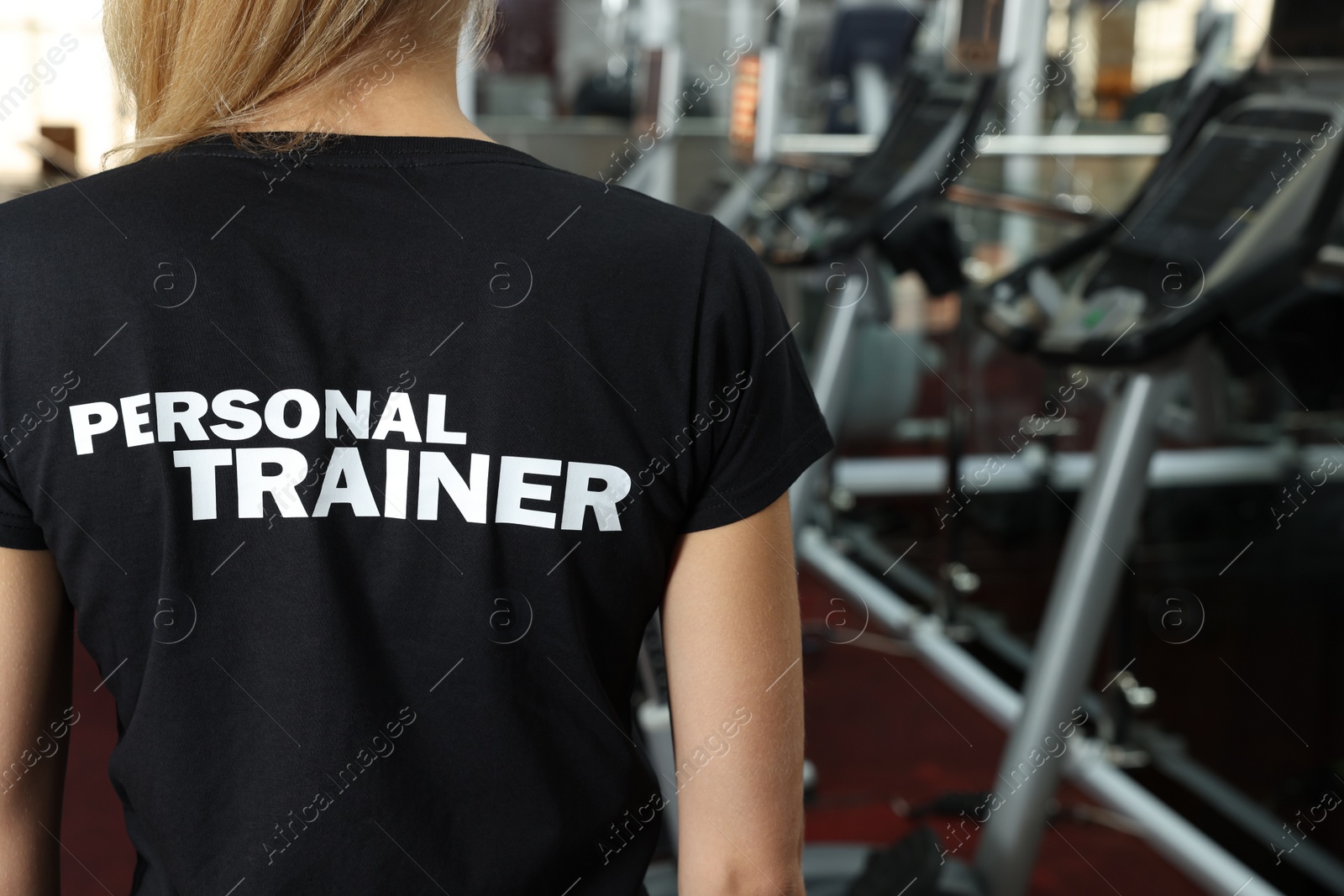 Photo of Personal trainer in modern gym, back view