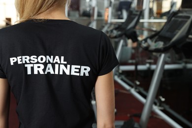 Photo of Personal trainer in modern gym, back view