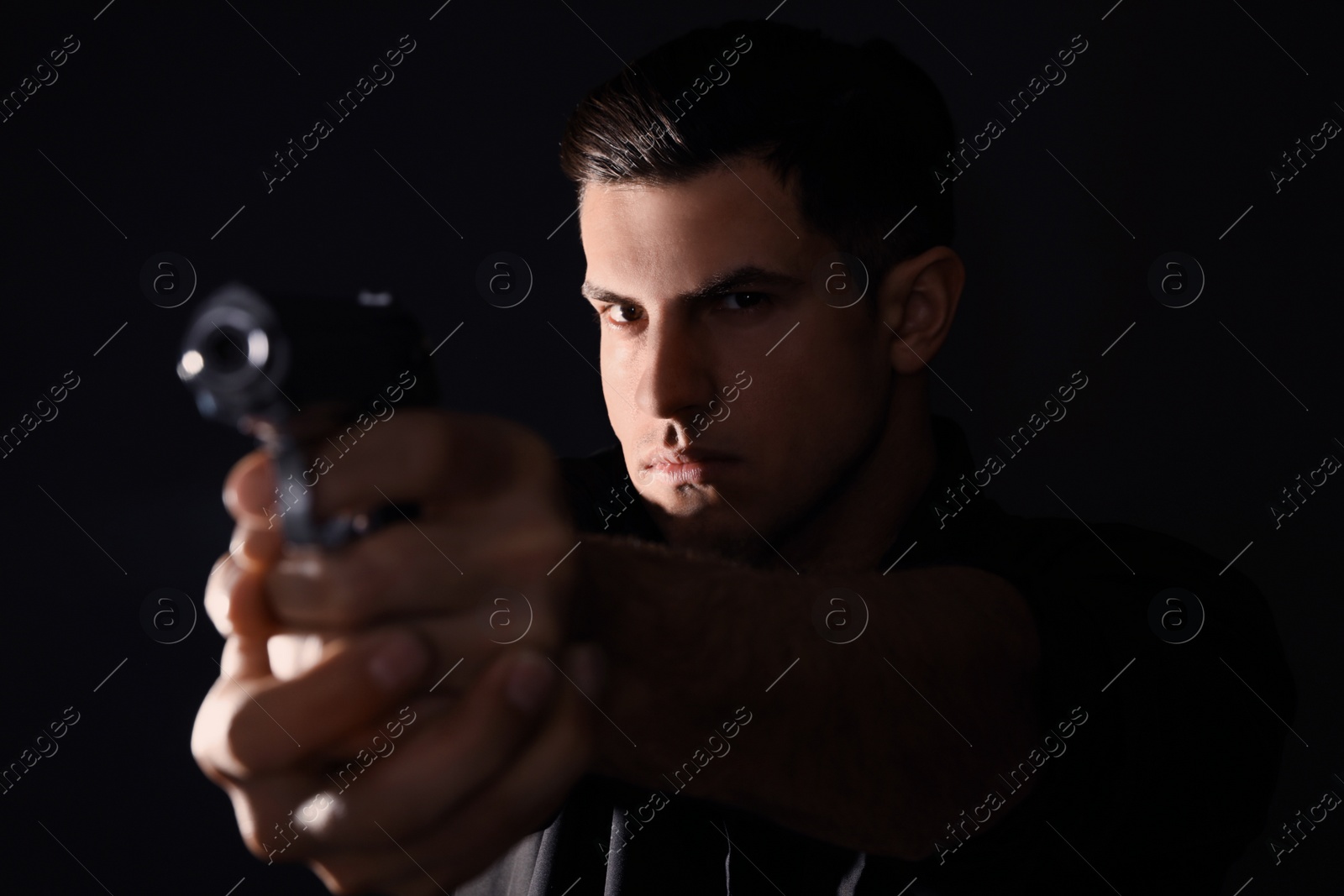 Photo of Professional killer with gun on black background