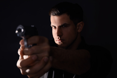 Photo of Professional killer with gun on black background