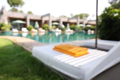 Sunbeds near swimming pool at luxury resort, blurred view