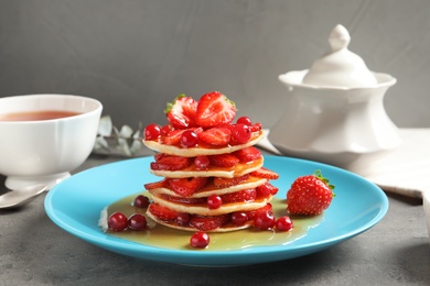 Photo of Tasty pancakes with berries and honey on plate