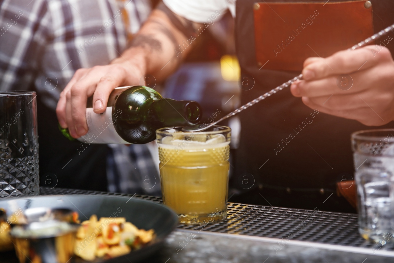 Photo of Bartender preparing tasty cocktail at counter in nightclub, closeup