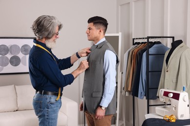 Photo of Professional tailor working with client in atelier