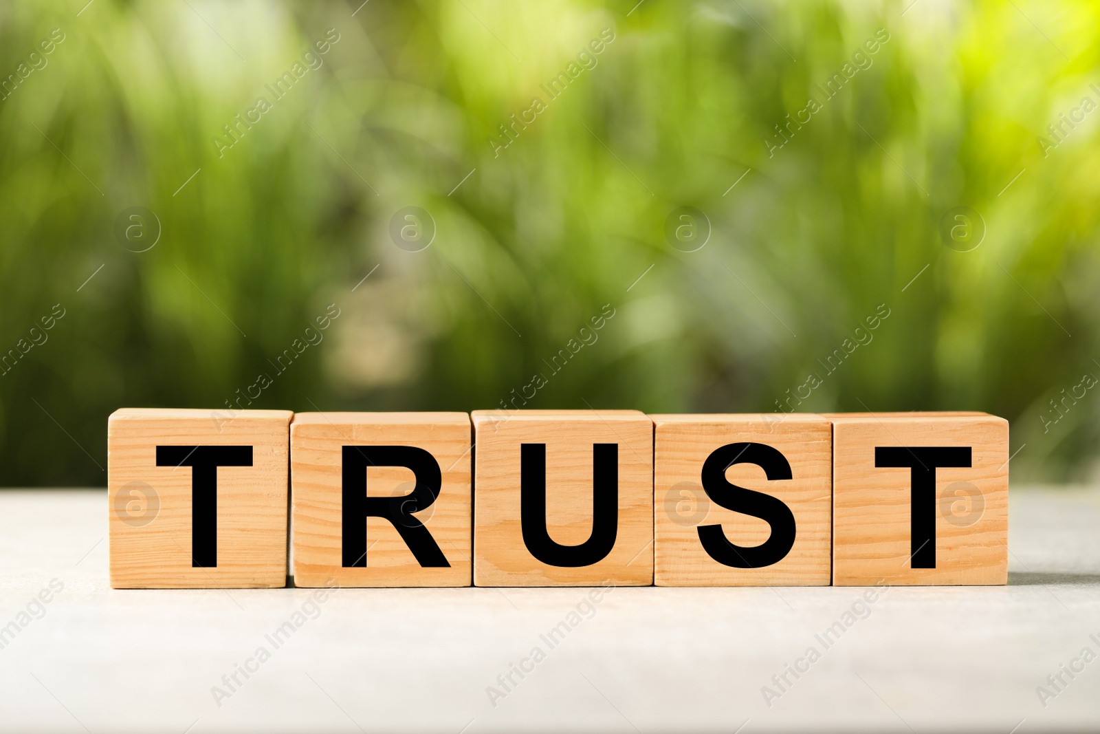 Photo of Word Trust made of wooden cubes on white table against blurred background