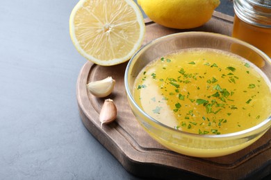 Photo of Bowl with lemon sauce and ingredients on dark table, space for text. Delicious salad dressing