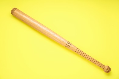 Photo of Wooden baseball bat on yellow background, top view. Sports equipment