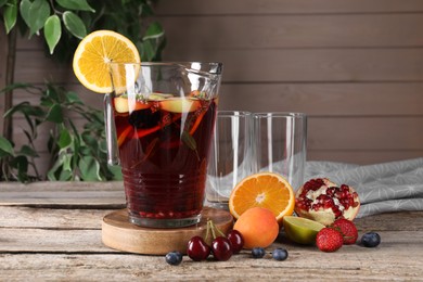 Photo of Delicious refreshing sangria with fruits and berries on old wooden table