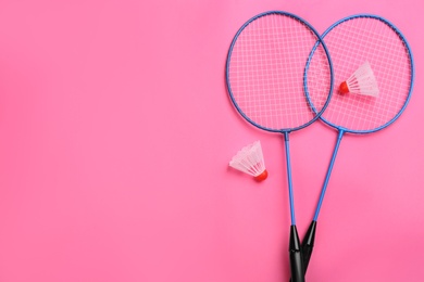 Rackets and shuttlecocks on pink background, flat lay with space for text. Badminton equipment